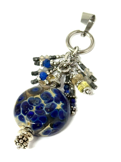 Handmade blue blown glass pendant with hand-beaded details. Features shades of blue, taupe, and gray in a unique interchangeable design.