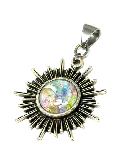 Handmade shining glass pastel sun pendant featuring a colorful center stone and detailed metal rays.