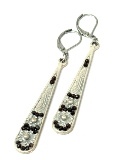 Long ruby faceted handmade dangle earrings featuring intricate beaded designs and stainless steel lever backs.