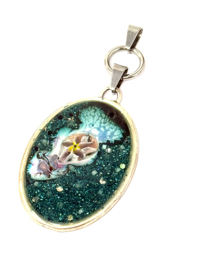This stunning oval pendant showcases a striking handmade copper enamel bead encircled by vibrant turquoise shimmer flakes and sparkling crystals.